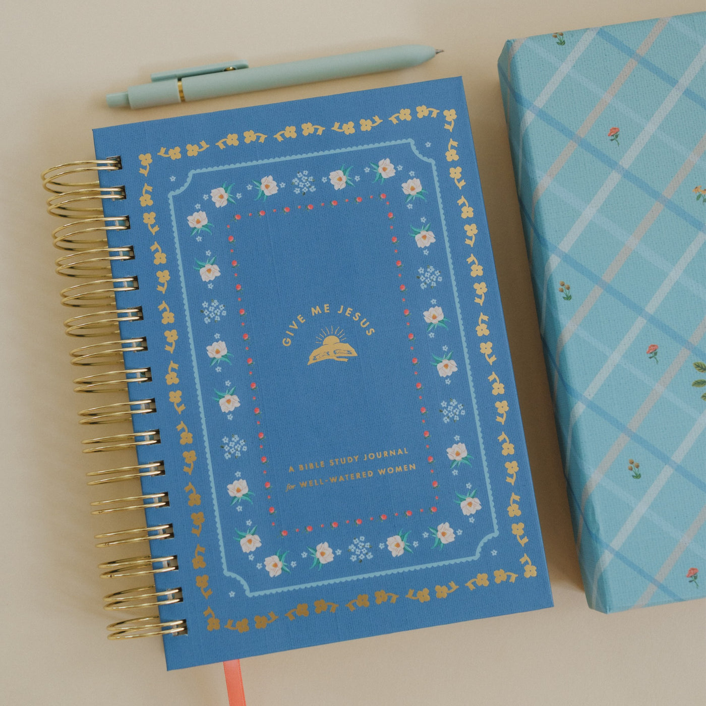 Give Me Jesus Journal with a blue floral cover displayed on a light surface alongside a matching pen and patterned box.