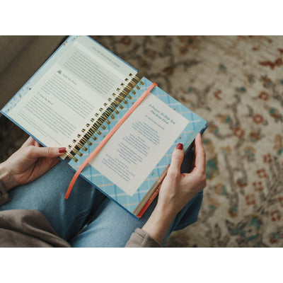 Woman reading the Give Me Jesus Journal open to the prayer and reflection pages while sitting on the couch.