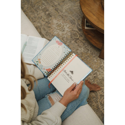 Woman sitting comfortably with the Give Me Jesus Journal open on her lap alongside an open Bible during quiet time.