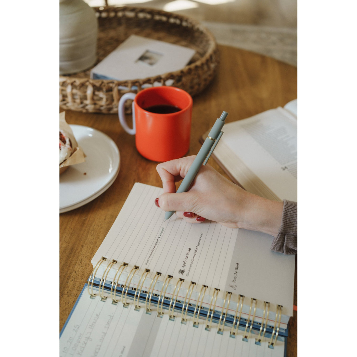 Woman writing in the Give Me Jesus Journal during morning Bible study with coffee and a pastry nearby.